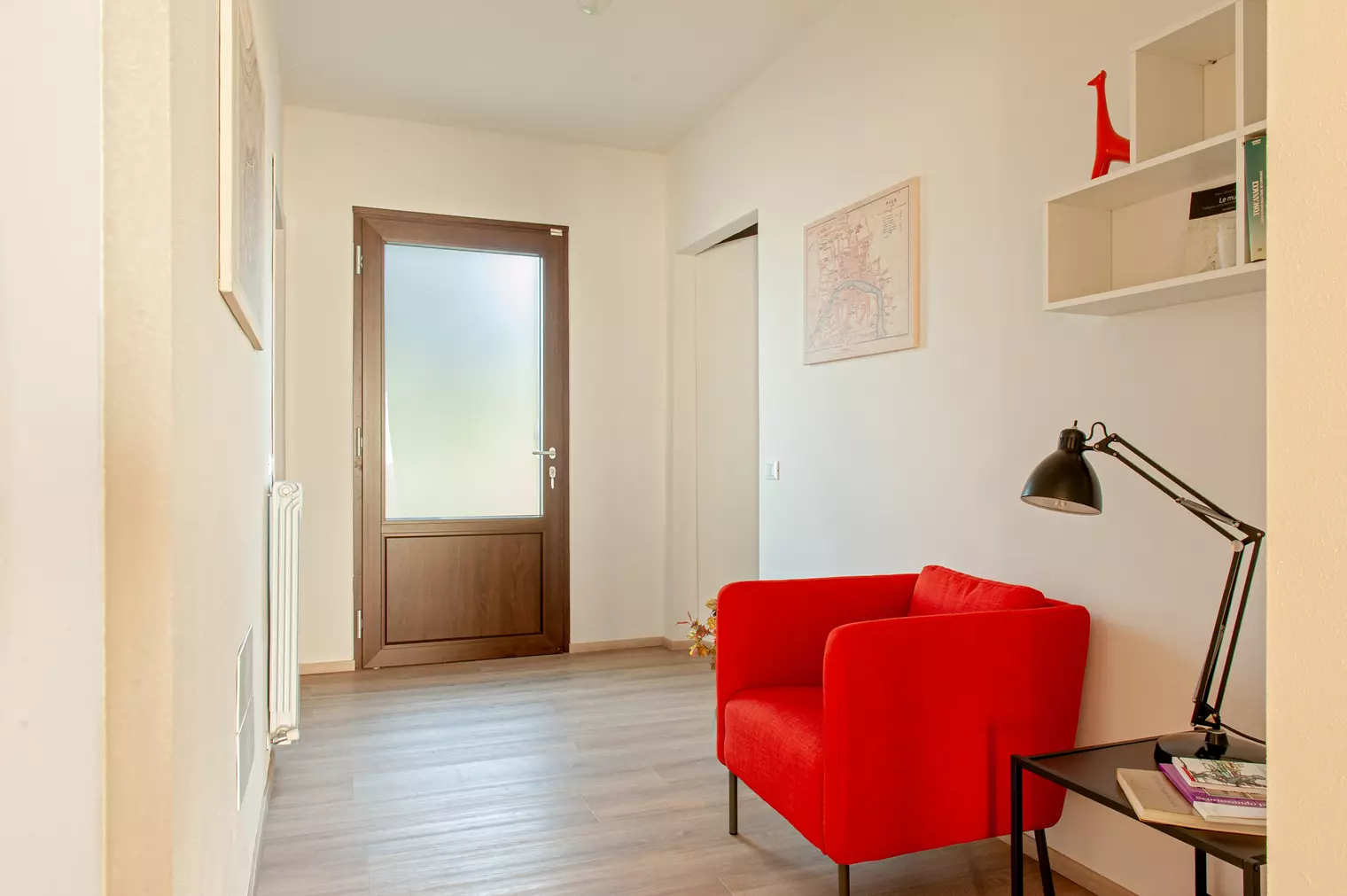 Red reading chair in a quiet corner of Appartamento La Quercia